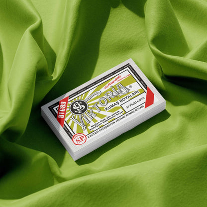 Pack of apple green fabric dye placed on a vibrant light green fabric background